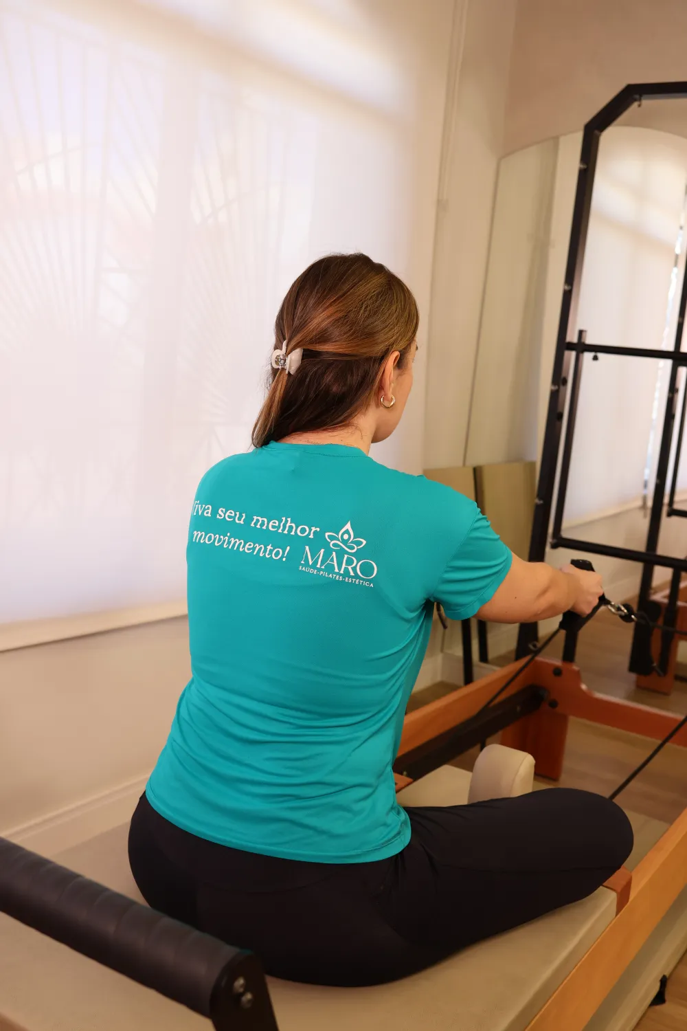 Aluna no reformer com a camiseta Viva seu melhor movimento