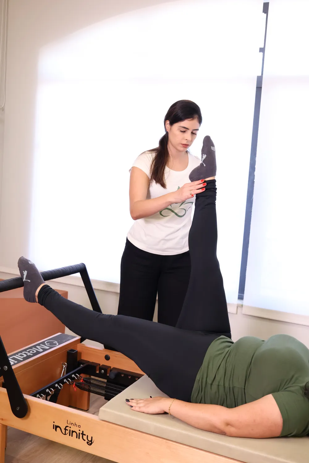 Instrutora corrigindo o exercício de uma aluna no reformer